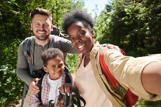 Ritratto di una famiglia felice di tre persone che fanno selfie ritratto sul telefono cellulare durante le escursioni
