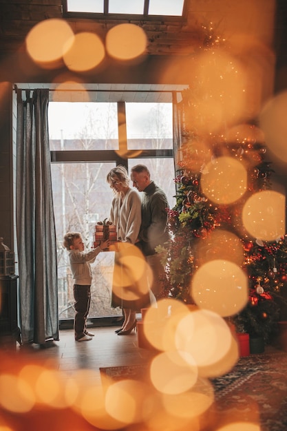 Ritratto di una famiglia felice in maglioni beige a maglia in attesa di Babbo Natale all'interno