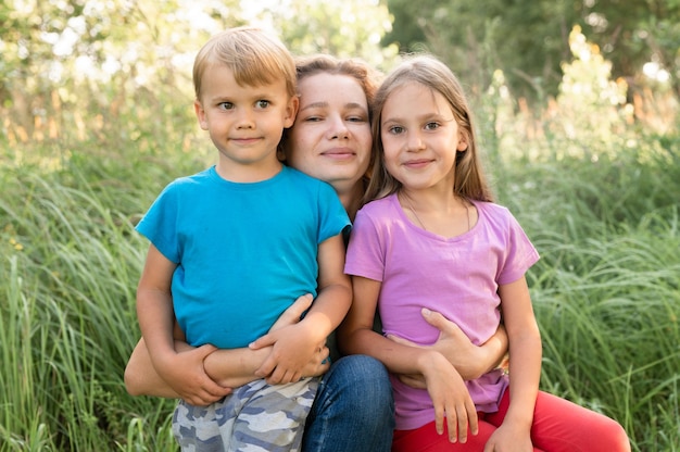 Ritratto di una famiglia felice, madre, figlio e figlia, in natura all'aperto in estate