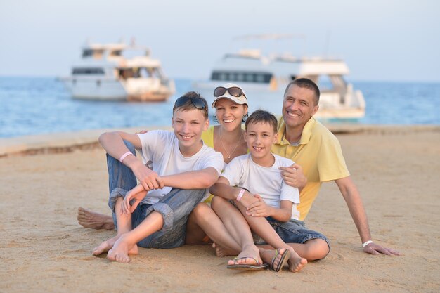 Ritratto di una famiglia felice seduta in spiaggia in estate