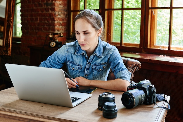 Ritratto di una fotografa ragazza che lavora con un computer