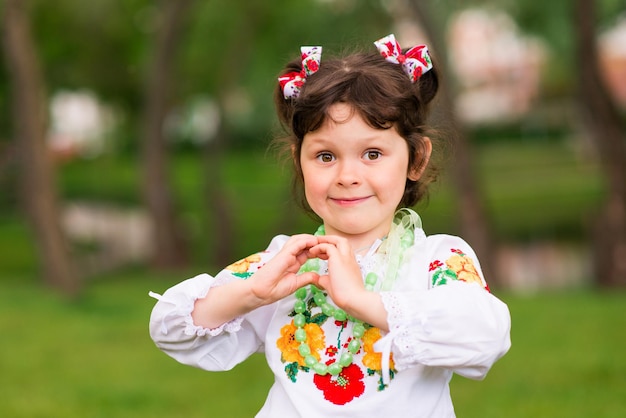 Ritratto di una gioiosa ragazza in abiti nazionali ucraini su sfondo verde. All'aperto.