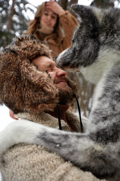 Ritratto di una giovane bella coppia di aspetto europeo con un cane husky nella foresta invernale