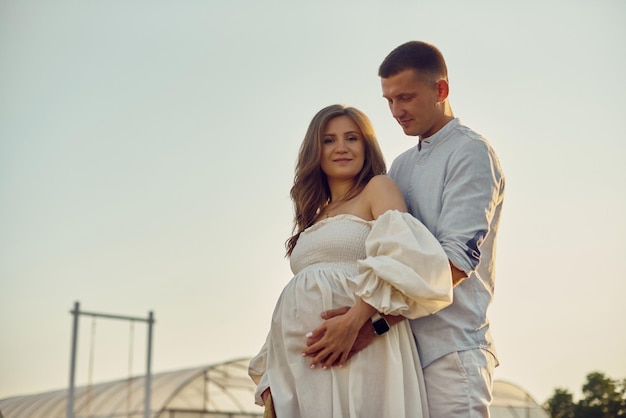 Ritratto di una giovane bella coppia incinta su un campo di lavanda al tramonto Concetto di famiglia felice