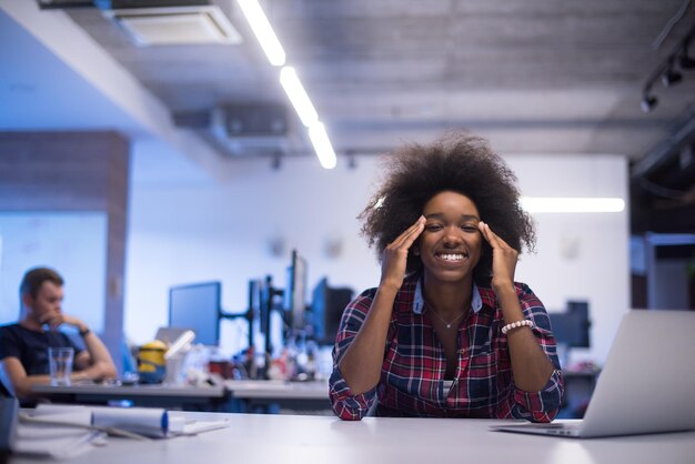 ritratto di una giovane bella donna afroamericana di successo che ama trascorrere un tempo gioioso e di qualità mentre lavora in un grande ufficio moderno