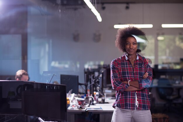 ritratto di una giovane bella donna afroamericana di successo che ama trascorrere un tempo gioioso e di qualità mentre lavora in un grande ufficio moderno