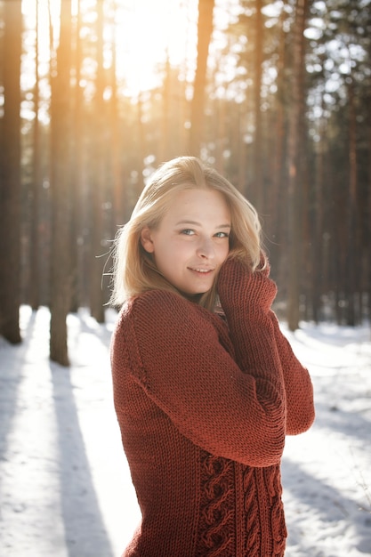 Ritratto di una giovane bella donna bionda in maglione in posa a winter park. Giornata di sole nella foresta.