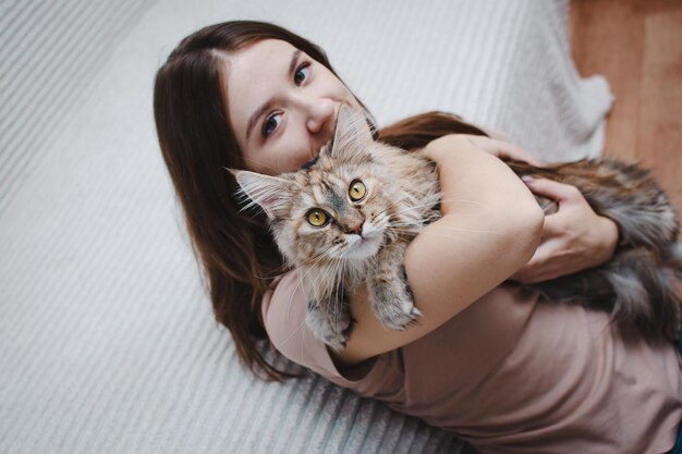 Ritratto di una giovane bella donna che abbraccia il suo gatto a casa