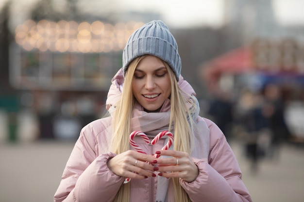 Ritratto di una giovane bella donna felice con caramelle in posa sulla strada di una città europea. Xmas.