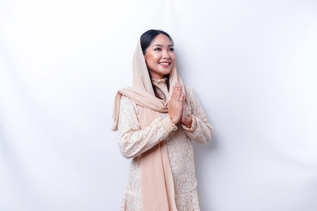 Ritratto di una giovane bella donna musulmana asiatica che indossa un hijab che gesturing il saluto di Eid Mubarak