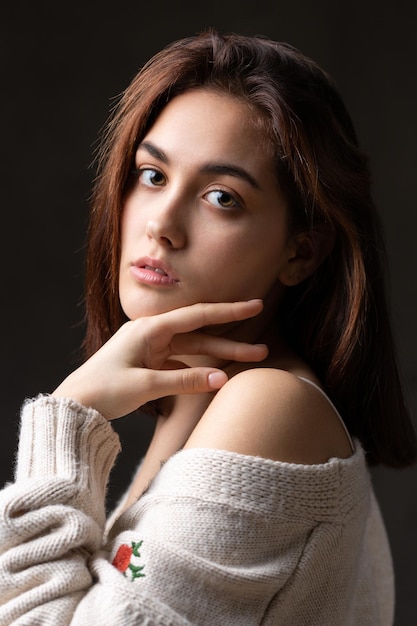 Ritratto di una giovane bruna con i capelli lunghi in studio Foto drammatica in colori scuri