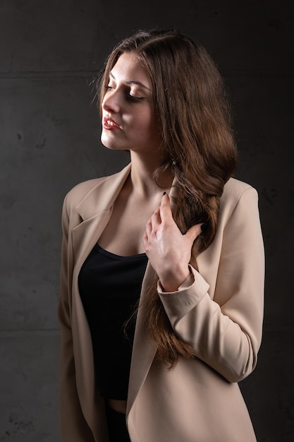 Ritratto di una giovane bruna con i capelli lunghi in studio Foto drammatica in colori scuri