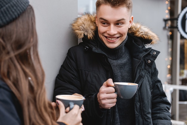 ritratto di una giovane coppia di innamorati felice in piedi vicino a caffè all'aperto bere caffè.