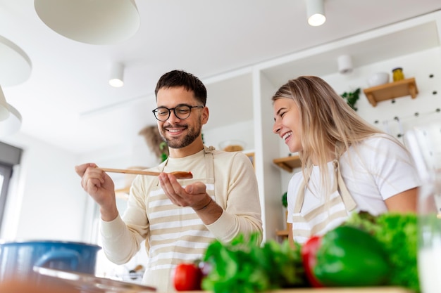 Ritratto di una giovane coppia felice che cucina insieme in cucina a casa romantica Una giovane donna attraente e un uomo bello si divertono a passare il tempo insieme mentre stanno in piedi su una cucina moderna luminosa