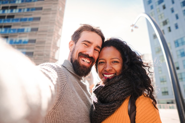 Ritratto di una giovane coppia multietnica sorridente che scatta una foto selfie con un telefono cellulare mentre fa un viaggio Concetto di viaggio