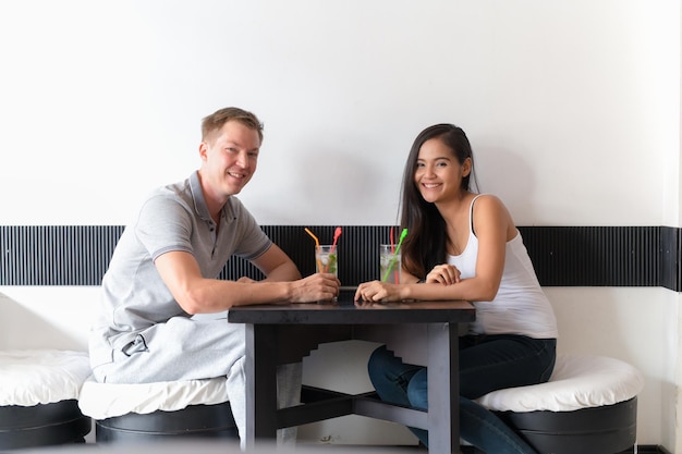 Ritratto di una giovane coppia sorridente seduta sul tavolo