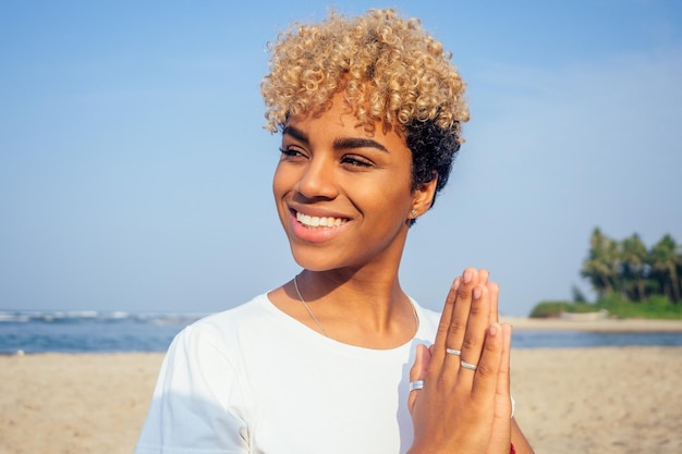 Ritratto di una giovane donna africana latina che si siede nella posa di yoga allo stile di vita della spiaggia