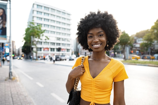 Ritratto di una giovane donna afroamericana sorridente in piedi in città