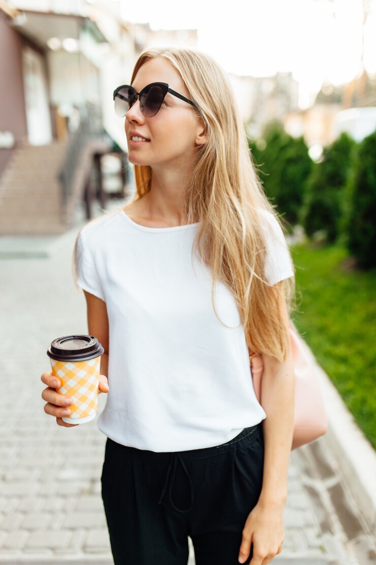 Ritratto di una giovane donna all'aperto e in possesso di una tazza di caffè. Ragazza che cammina per la città e bere caffè.