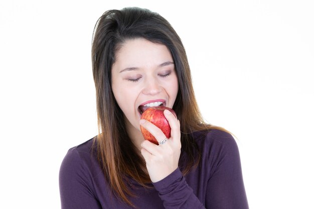 Ritratto di una giovane donna allegra che mangia mela rossa