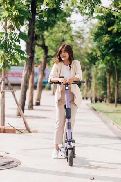 Ritratto di una giovane donna asiatica che guida uno scooter elettrico nel parco