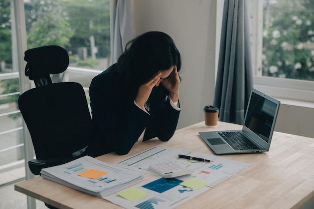 Ritratto di una giovane donna asiatica che lavora come freelance su un computer in un ufficio moderno Fare analisi contabile rapporto dati di investimento immobiliare Concetto di sistemi finanziari e fiscali