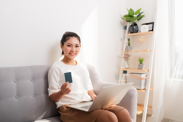 Ritratto di una giovane donna asiatica che tiene in mano una carta mentre si utilizza il laptop