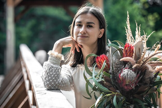 Ritratto di una giovane donna attraente con un mazzo di fiori esotici, un mazzo di fiori di protea.