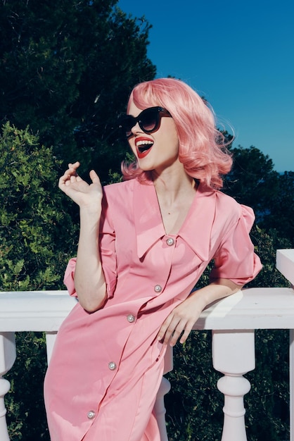 Ritratto di una giovane donna bella abito rosa stile moderno si trova vicino alla ringhiera giornata di sole