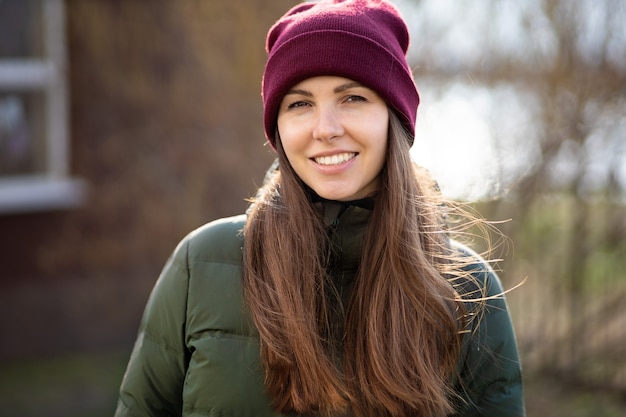 Ritratto di una giovane donna bruna carina con un cappello e una giacca caldi nel pomeriggio all'aperto