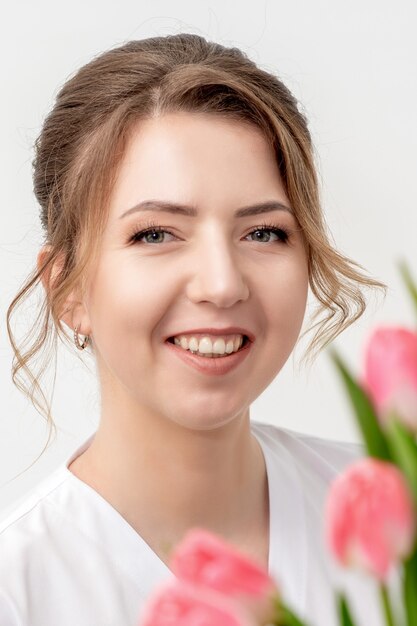 Ritratto di una giovane donna caucasica felice con tulipani rosa su uno sfondo bianco