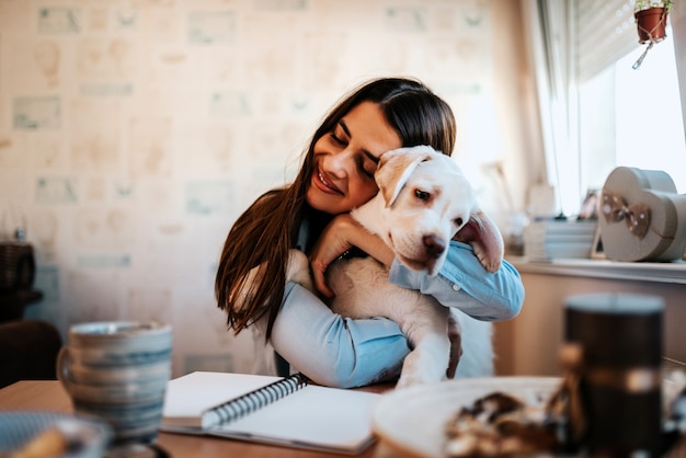 Ritratto di una giovane donna che abbraccia cucciolo all&#39;interno.