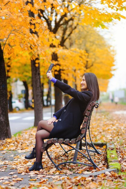 Ritratto di una giovane donna che cattura un selfie nella sosta di autunno