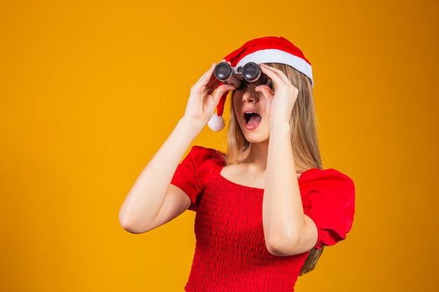 Ritratto di una giovane donna che indossa abiti natalizi guardando attraverso un binocolo