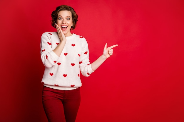 Ritratto di una giovane donna che indossa il ponticello alla moda alla moda isolato sulla parete rossa