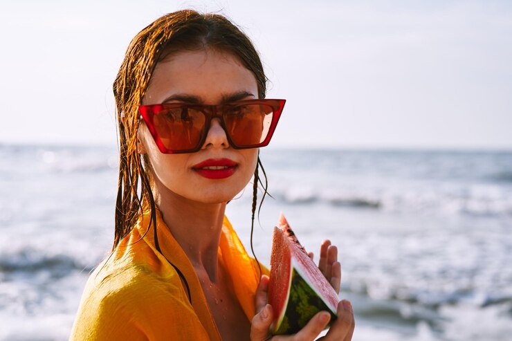 Foto ritratto di una giovane donna che indossa occhiali da sole contro il mare