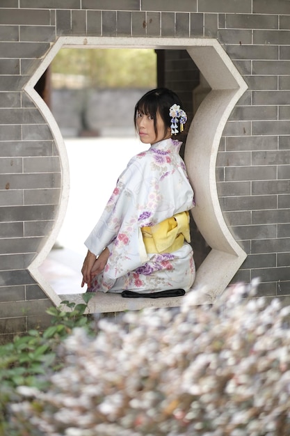 Ritratto di una giovane donna che indossa un kimono mentre è seduta alla finestra