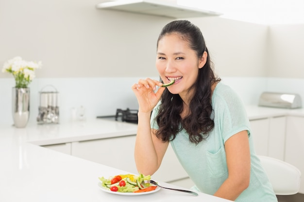 Ritratto di una giovane donna che mangia insalata in cucina