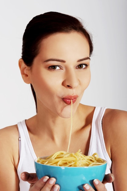 Ritratto di una giovane donna che mangia noodles su uno sfondo bianco
