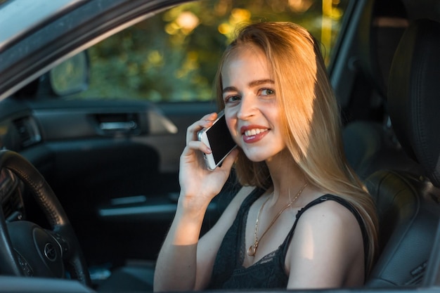 Ritratto di una giovane donna che parla su uno smartphone mentre è seduta in macchina