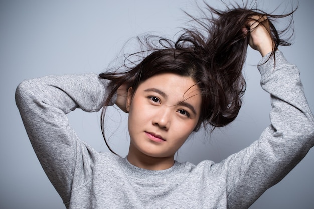 Ritratto di una giovane donna che tiene i capelli contro la parete