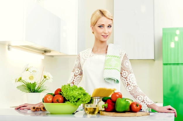 Ritratto di una giovane donna con gli ingredienti in cucina