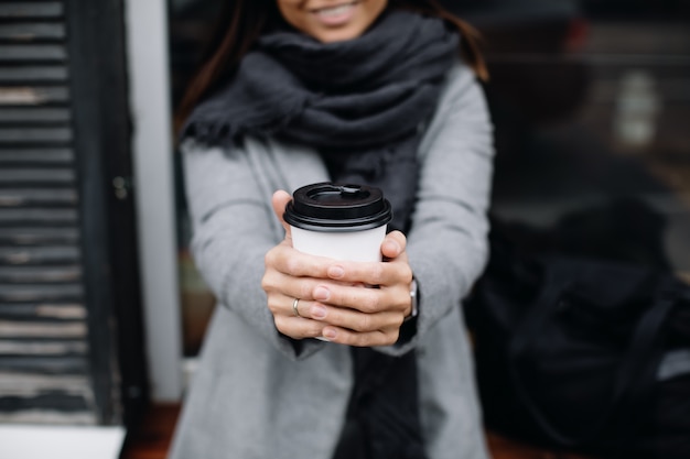 Ritratto di una giovane donna con gli occhiali. Una giovane donna d'affari si trova alla finestra di un bar e beve il caffè