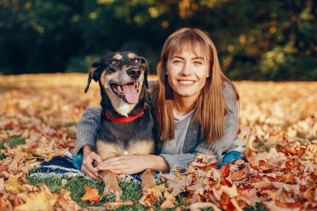 Ritratto di una giovane donna con un cane sdraiato sulle foglie durante l'autunno
