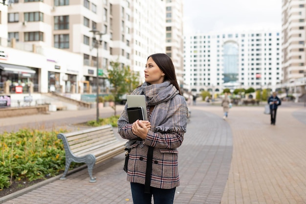 Ritratto di una giovane donna con un laptop in mano sullo sfondo degli edifici della città