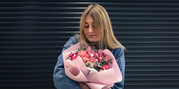 Ritratto di una giovane donna con un mazzo di fiori rosa su sfondo nero