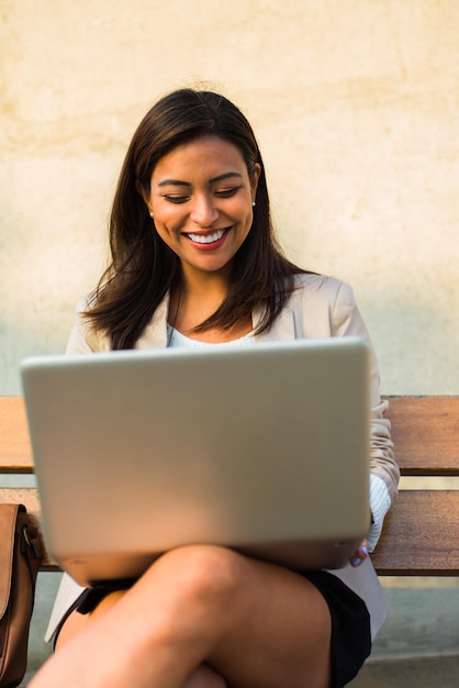 Ritratto di una giovane donna d'affari sorridente attraente che lavora al suo computer portatile mentre era seduto all'aperto Copia spazio