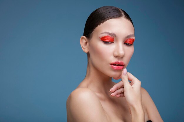 Ritratto di una giovane donna elegante con trucco luminoso rosso su sfondo blu. Moda di bellezza