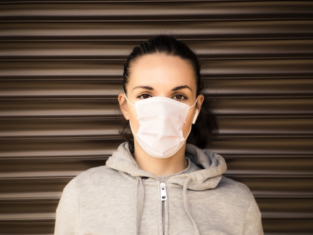 Ritratto di una giovane donna europea in una maschera medica. Bruna in una maschera medica con uno sguardo dritto.