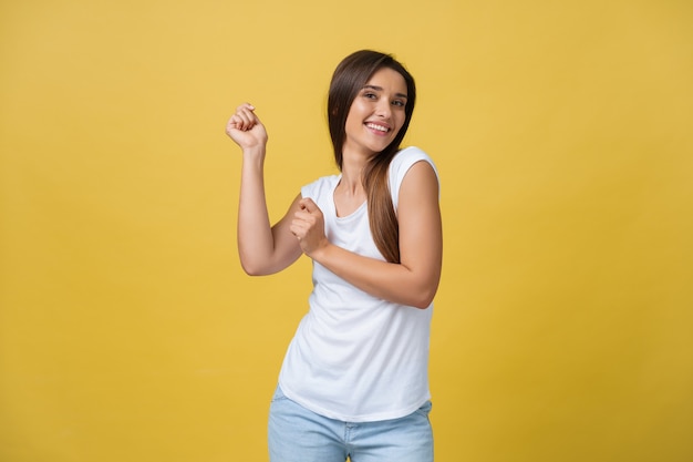 Ritratto di una giovane donna felice che balla su sfondo giallo